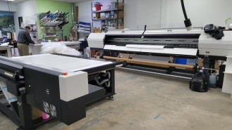 A full view of the Mimaki UJV55-320 roll-to-roll printer to the left.