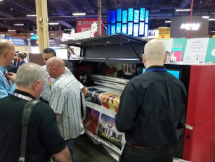 Attendees at the ISA Expo visit the EFI booth to see the new EFI Pro 16h wide-format hybrid roll/flatbed LED printer. 