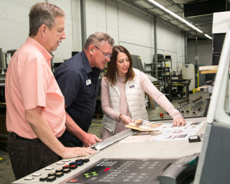 From left) Donnie Burrell, director of operations (Jacksonville Division); Vergil Backes, pressman; and Christa Nuckols, director of account managers, review a press sheet from a five-color M110 heatset web offset press.
