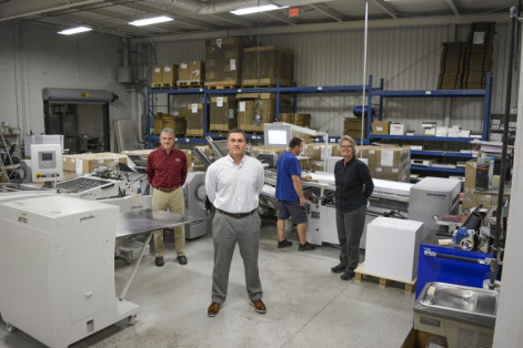 Standing, from the left, are Chip Bell, VP of sales; Adam Monk, president; and Sheila Southall, VP of production. In the background, Danny Rhodes, bindery technician, operates a Heidelberg Stahl folder with Palamides delivery.