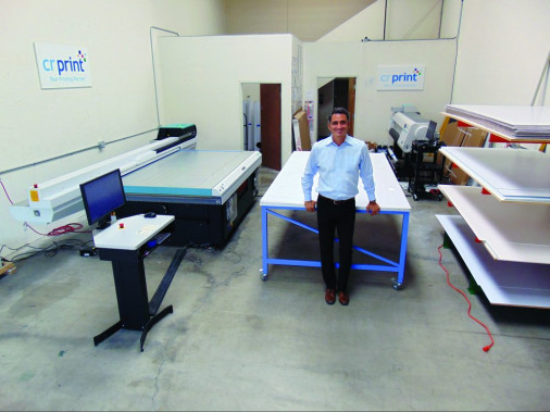 Mike Corridori, the owner of Westlake Village, Calif.-based CR Print, stands with his print shop&rsquo;s Fujifilm Acuity flatbed printer, which was installed just before the pandemic hit in February 2020.