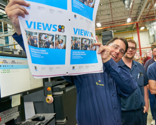 Governor Walker shows off digitally printed pages featuring a welcome message and pictures for the governor.